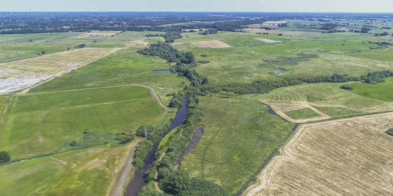Luftbild der Wümme mit durchgehendem Gehölzsaum umgeben von landwirtschaftlich genutzten Grünlandflächen