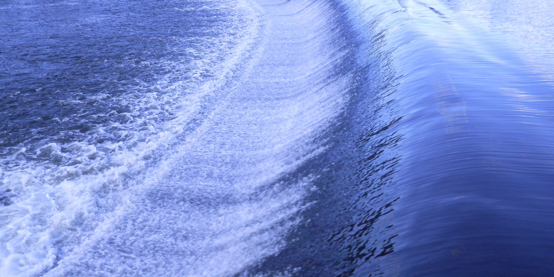 Foto: Ein von Wasser überflossenes, sichelförmiges Wehr.