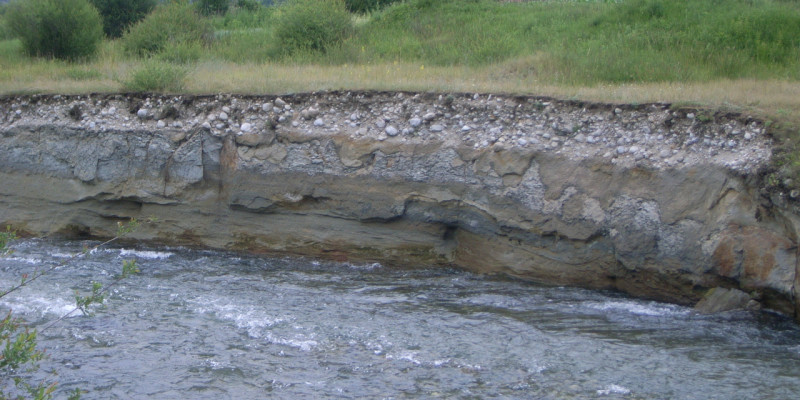 Foto: Ein Uferabbruch, an dem der unter der Vegetationsdecke liegende Schotterkörper sichtbar wird. 