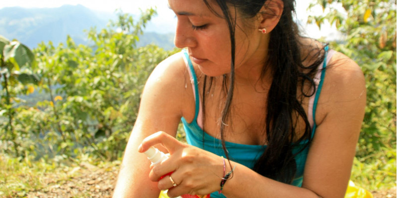 Eine Frau sprüht sich mit Mückenschutzspray ein
