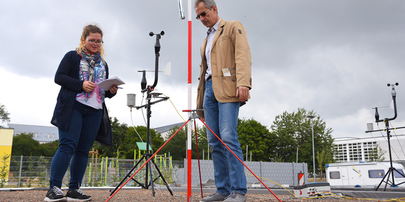 Eine Frau und ein Mann nehmen Daten eines Messgerätes auf einem Flachdach