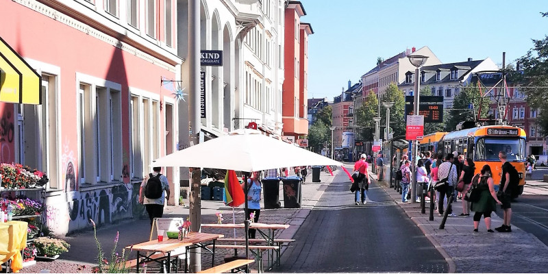 Ansicht des Lindenauer Markts ohne Autos. Es ist eine Straßenbahn und eine leere Straße zu sehen.