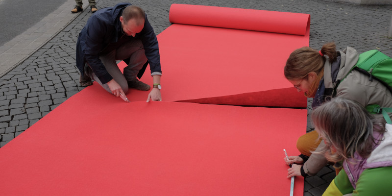 Teilnehmende schneiden den roten Teppich an der richtigen Stelle zu