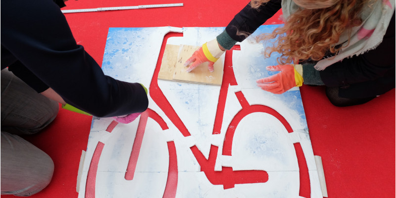 Teilnehmende sprühen das Fahrradsymbol auf den roten Teppich