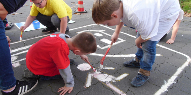 Kinder malen ihr Verkehrszeichen auf den Boden