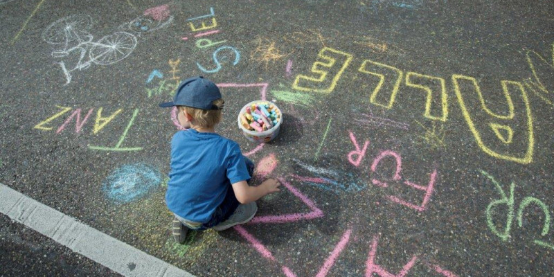 Kind malt auf der Straße mit Straßenkreide