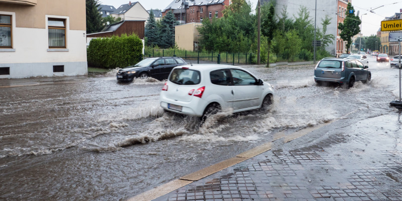 Auto fährt überflutete Straße entlang