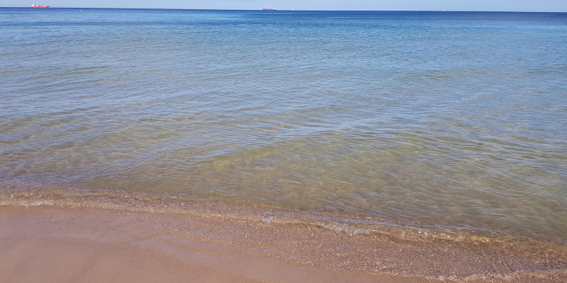 Leerer Sandstrand, kleine Wellen.