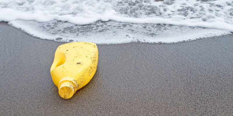Gelbe Plastikflasche am Strand