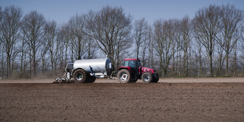 Großaufnahme eines Traktors, der auf einem Feld Gülle ausfährt