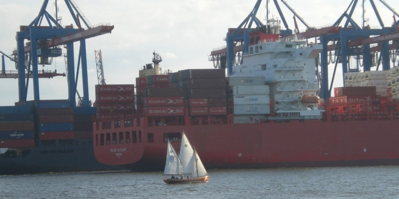 Sailing boat and container ship in the harbor of Hamburg