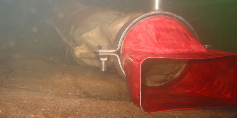 Unterwasseraufnahme: auf dem sandigen Grund liegt Röhre aus einem ausgestieften Fliesstoff