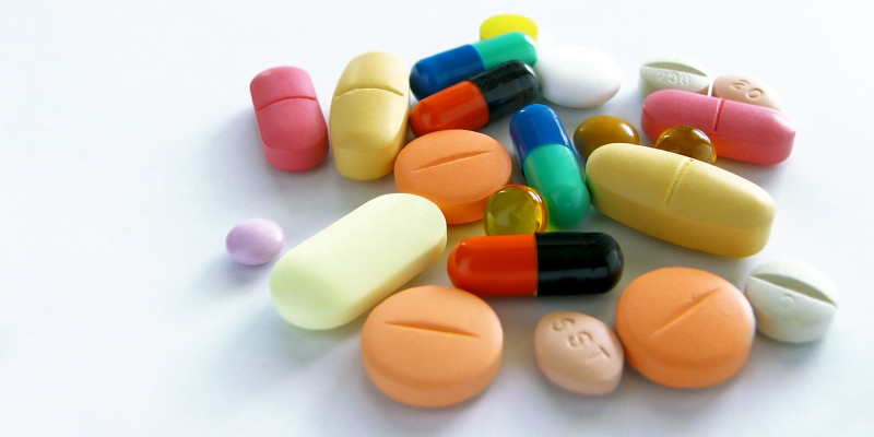 Tabletten in verschiedenen Formen und Farben liegen auf einem weißen Untergrund