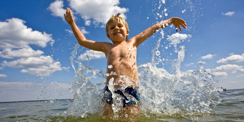 ein kleiner Junge tobt lachend im Meer oder in einem großen Badesee