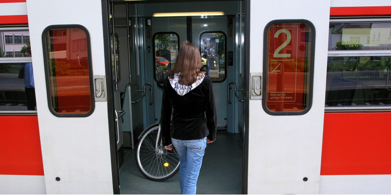 eine junge Frau steigt in eine Regionalbahn, in der sich ein Fahrrad befindet