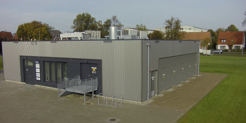 einstöckiges, quadratisches Betongebäude mit Flachdach, auf dem Dach einige technische Aufbauten