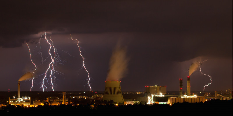 über einer Industrieanlage bei Nacht tobt ein Unwetter mit Blitzen und dunklen Wolken