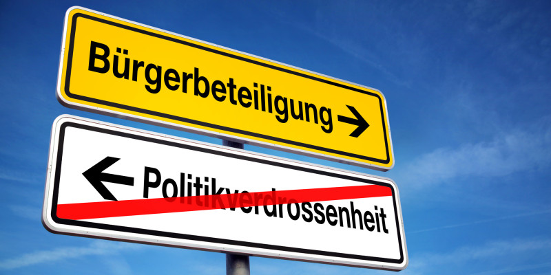 Ein Schild weist in Richtung „Bürgerbeteiligung“, „Politikverdrossenheit“ mit einem rückwärts gewandten Pfeil ist durchgestrichen