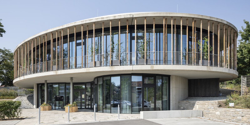 modernes, 2-geschossiges, rundes Gebäude aus Beton, Glas und Holz