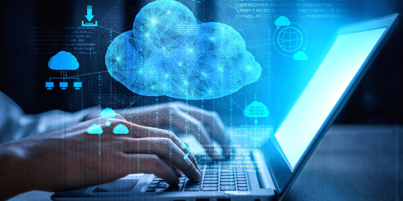 jemand tippt auf einem Laptop, darüber Symbole für Cloud Computing wie Wolken und Download-Pfeil