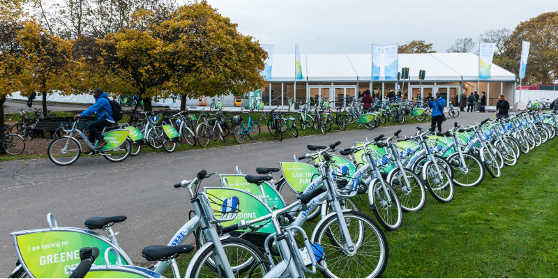 vor einem Gebäude stehen viele gleiche Fahrräder mit dem Logo der 23. Weltklimakonferenz in einer Reihe