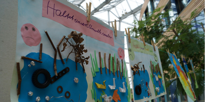 Kinderbilder zu Umweltthemen hängen mit Wäscheklammern an einer Leine im Eingangsbereich des UBA Dessau-Roßlau
