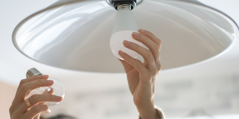 eine Frau tauscht eine Glühbirne gegen eine LED-Lampe aus