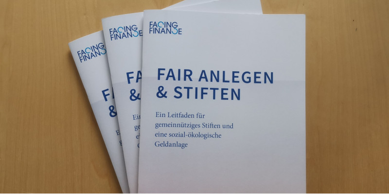 drei Druckversionen des Leitfadens "Fair anlegen & stiften", auf dem Cover sind Windkraftanlagen abgebildet