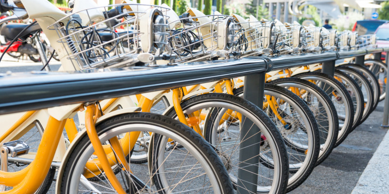 gelbe Leihfahrräder in einer Reihe in einem langen Fahrradständer