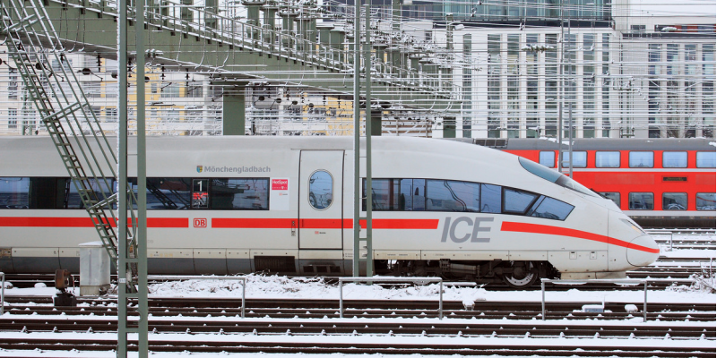 moderner ICE-Schnellzug auf einem verschneiten Gleis in der Stadt