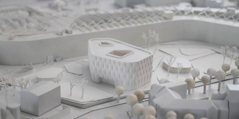 von Architekten gebautes, ganz in weiß gehaltenes Modell eines modernen vierstöckigen, polygonalen Flachbaus und seiner Umgebung
