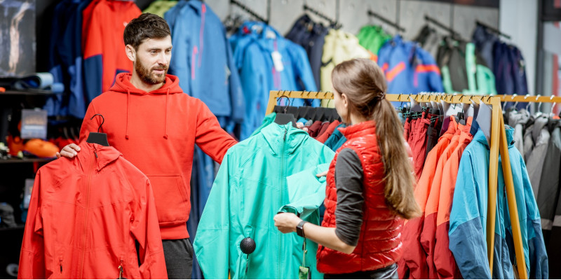 ein junges Pärchen sucht in einem Geschäft zusammen eine wetterfeste Jacke aus