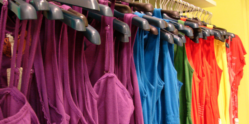 pink, blue, green, red and yellow tops hanging on clothes hangers in a shop