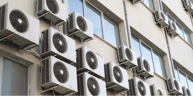 viele Klimaanlagen-Kästen an einer Hausfassade