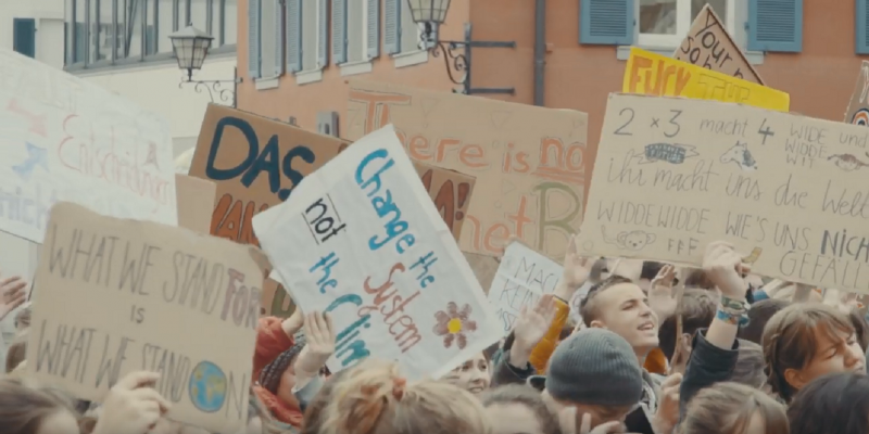 Jugendliche auf einer Demonstration halten Plakate für mehr Klimaschutz in die Luft 