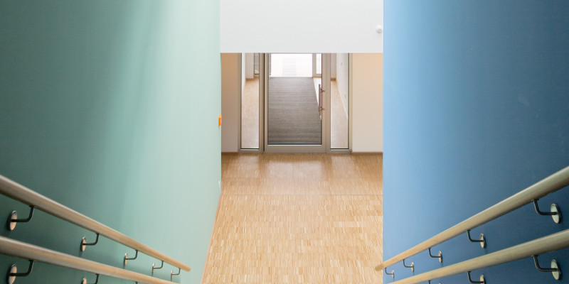 Treppe abwärts mit Holz-Handläufen, die rechts Wand ist blau, die linke in einem hellen grün-blau gestrichen