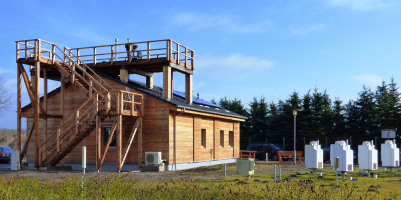 einstöckiges Holzhaus, eine Treppenanlage führt zu einer Plattform auf dem Dach