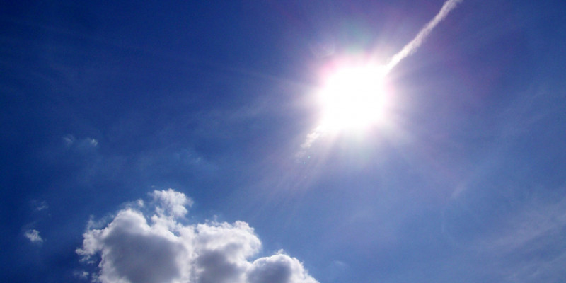 strahlende Sonne an einem blauen Himmel mit Schönwetterwolke