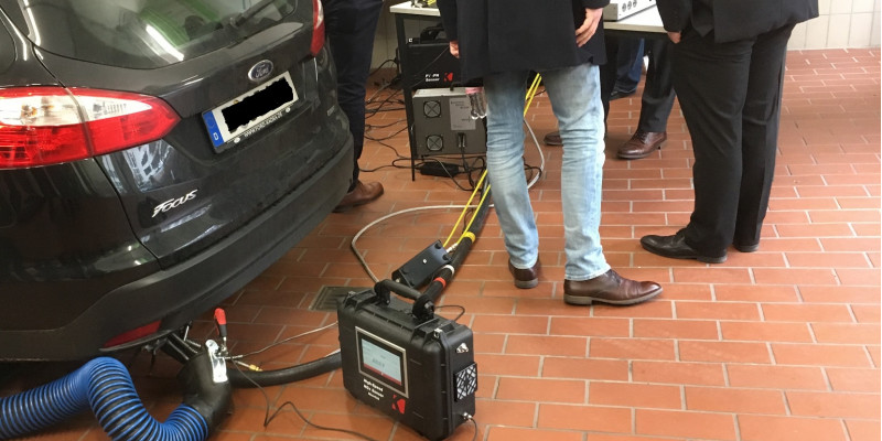 an einem Pkw, der in einem Raum steht, ist ein Messgerät am Auspuff angeschlossen