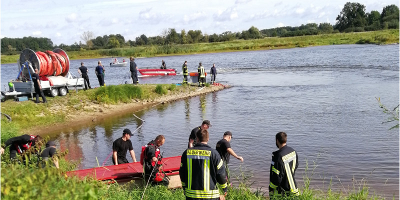 Feuerwehrleute mit Booten an und auf einem Fluss im Einsatz