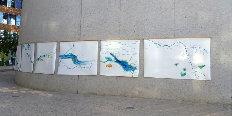 im Vorraum des Umweltbundesamtes Dessau hängen große weiße Bilder nebeneinander, auf denen ein Flusslauf gemalt ist