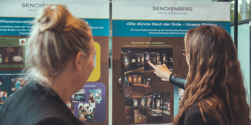 Teilnehmer vor einem Infoplakat