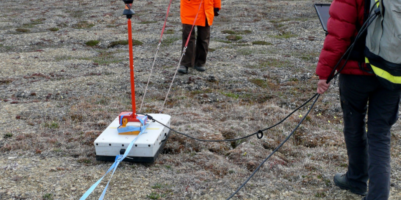 Zwei Forscherinnen stehen mit ihren Instrumenten in der arktischen Landschaft.