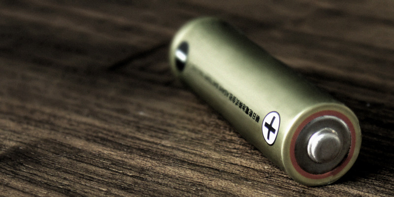 Eine einzelne Batterie liegt auf einem Holztisch