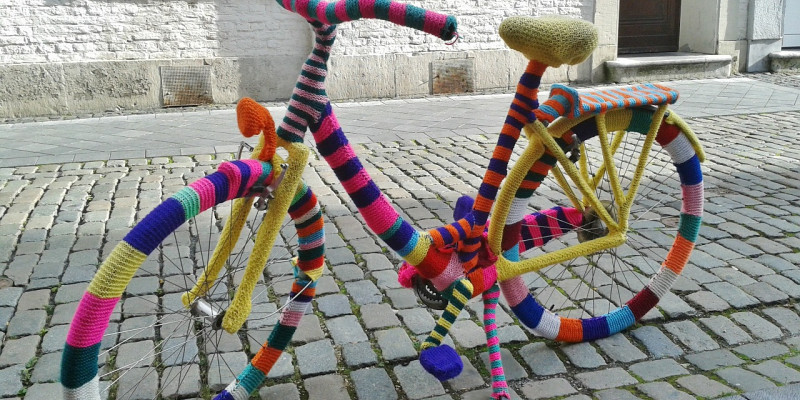 Ein Fahrrad, das komplett mit bunter, gestrickter Wolle umhüllt wurde