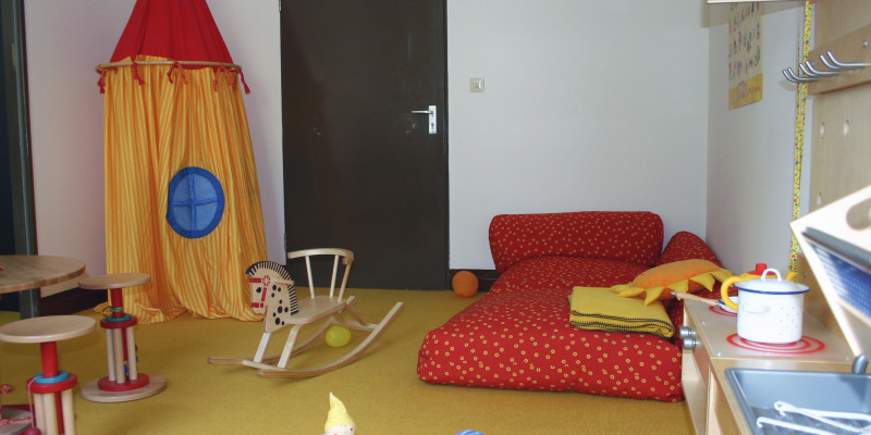 Eltern-Kind-Zimmer: eine Spielecke mit Matratze, Spielküche, Sitzecke und Spielzelt aus Stoff
