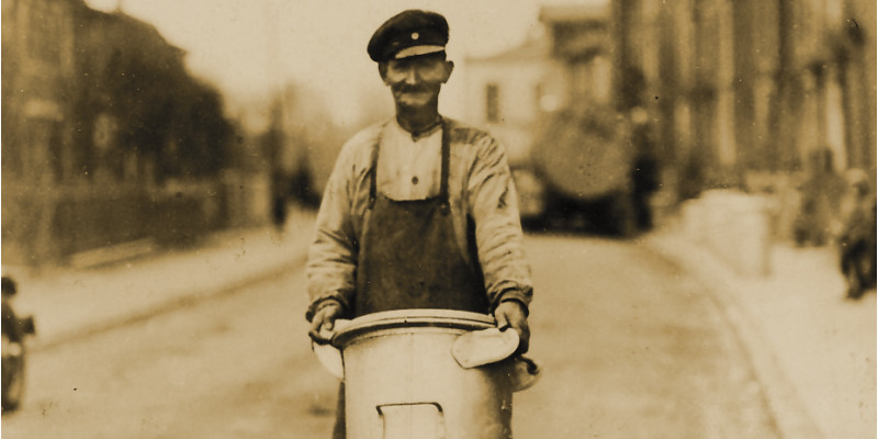 Ein Mann trägt eine hohe Mülltonne auf der Straße