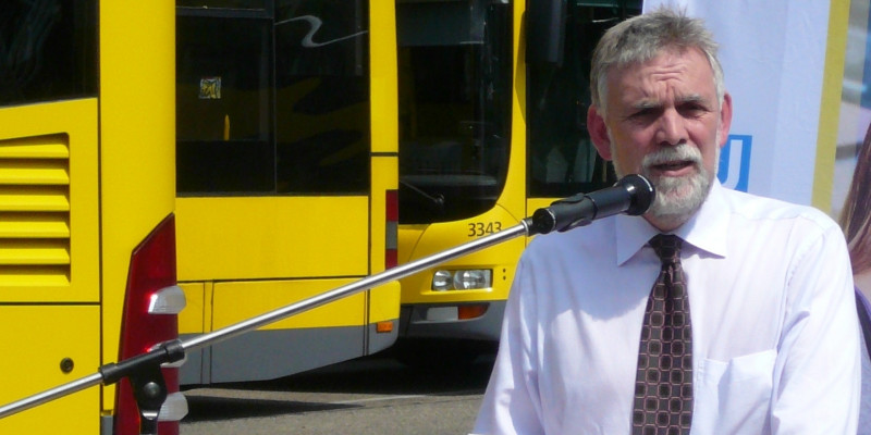 the former UBA President Jochen Flasbarth making a speech, in the background yellow busses