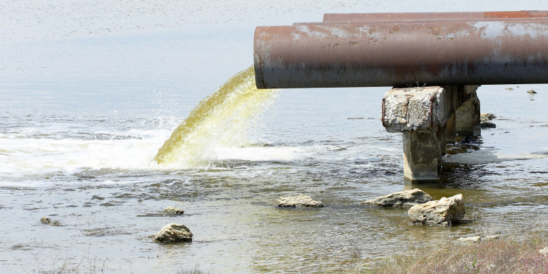 Aus einem Rohr fließt Abwasser in ein Gewässer