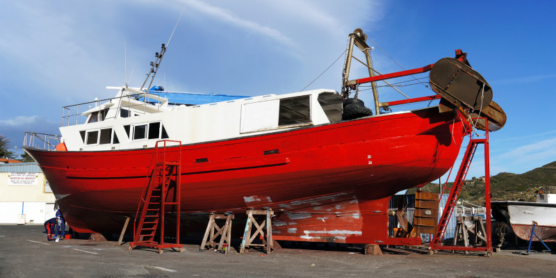 rotes Fischerboot liegt in der Werft, wird neu angestrichen